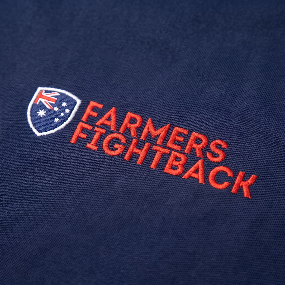 Close up of the embroidered Farmers Fightback badge on midnight blue fabric