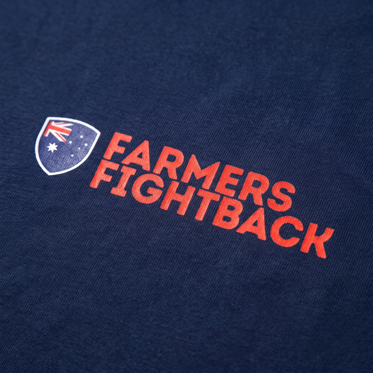 Close up of the screen printed Farmers Fightback logo on a navy tee