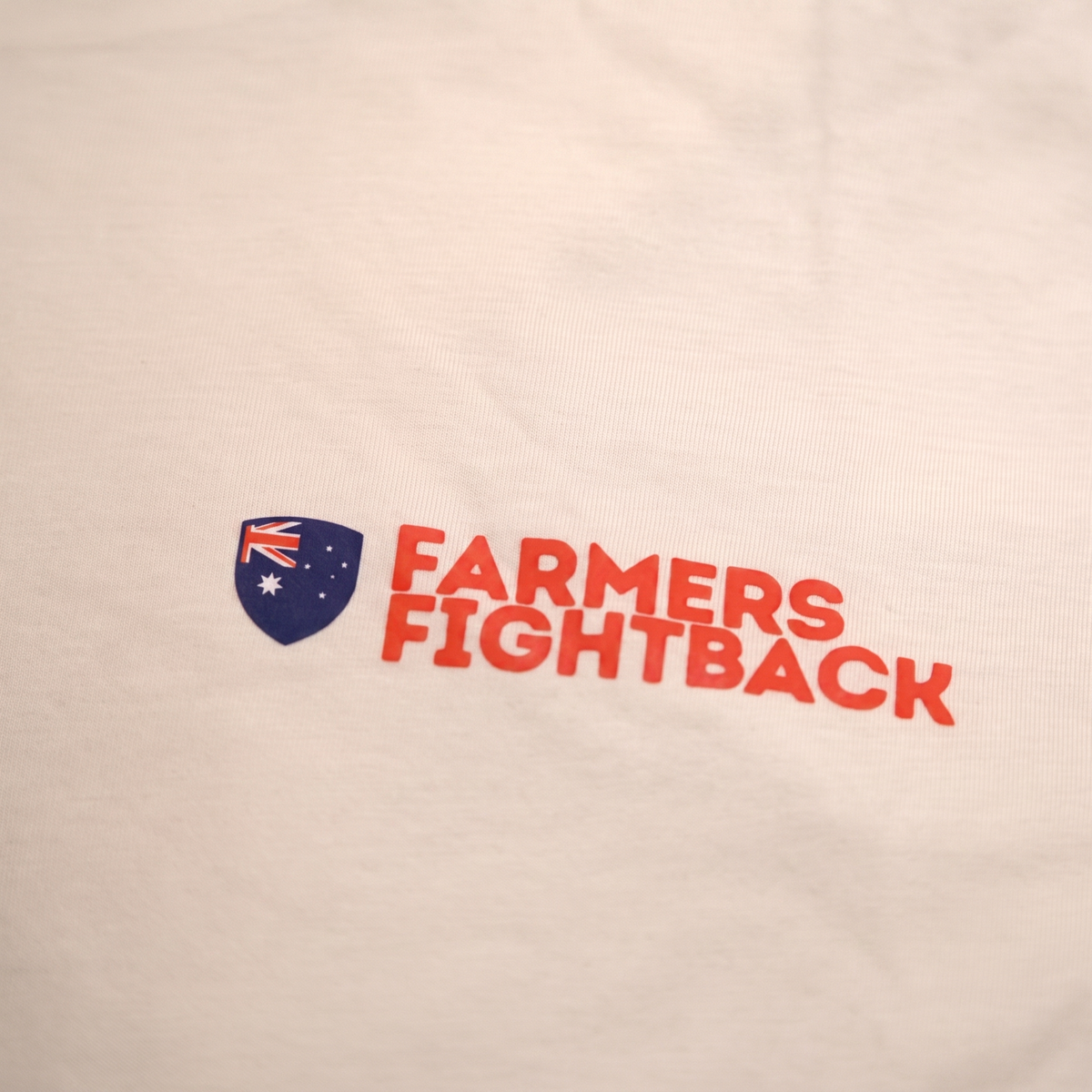 Close up of the screen printed Farmers Fightback logo on a cream tee
